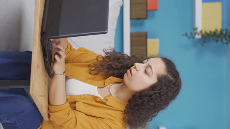 Vertical-video-of-Young-woman-looking-at-laptop-is-thoughtful.